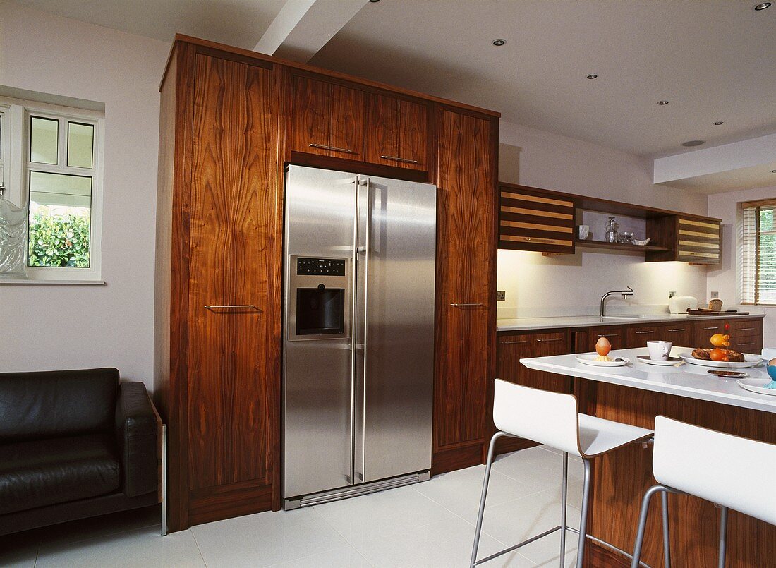 Offene Küche mit Schrankfronten aus Holz und Kühlschrankkombination aus Edelstahl