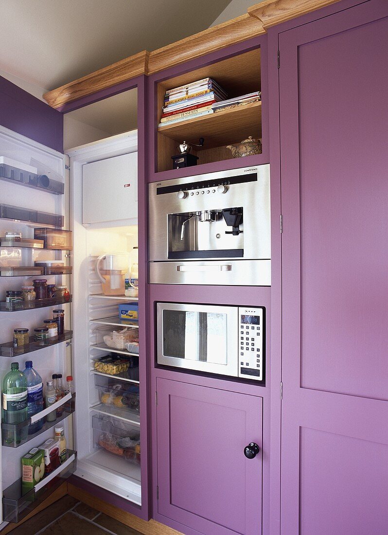 Violetter Einbauschrank mit Kühl-Gefrierkombination und offener Tür neben Einbaugeräten