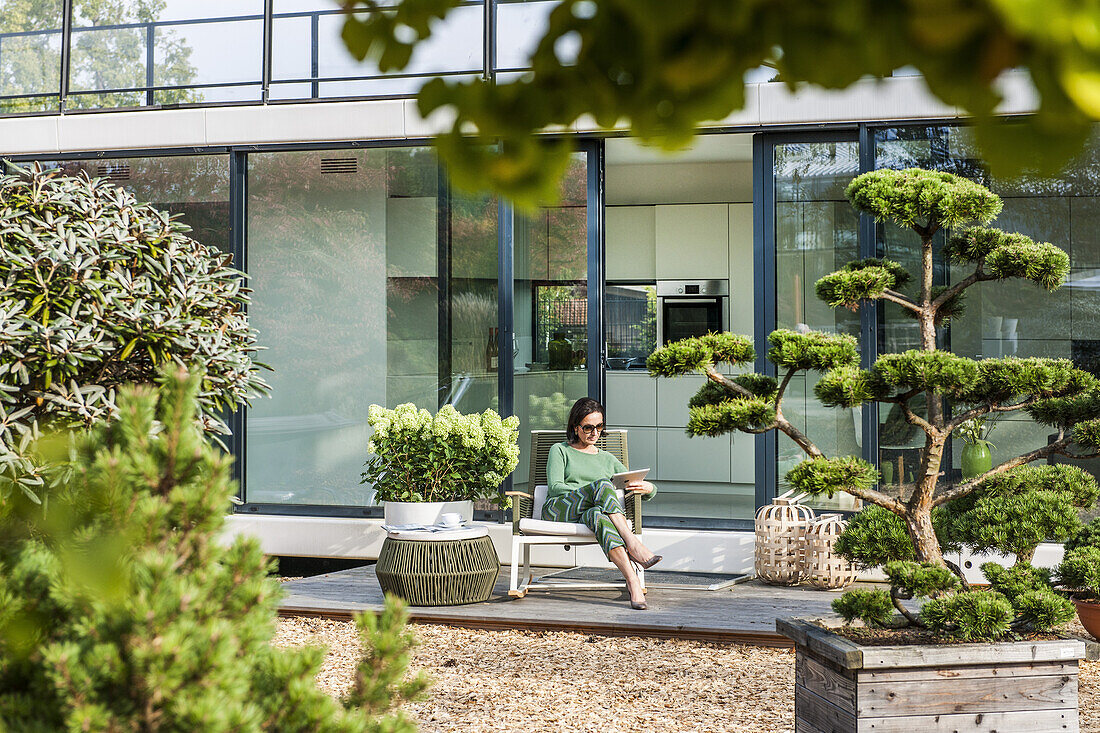 woman sitting on a terrace with an iPad,modern architecture in Hamburg,north Germany,Germany