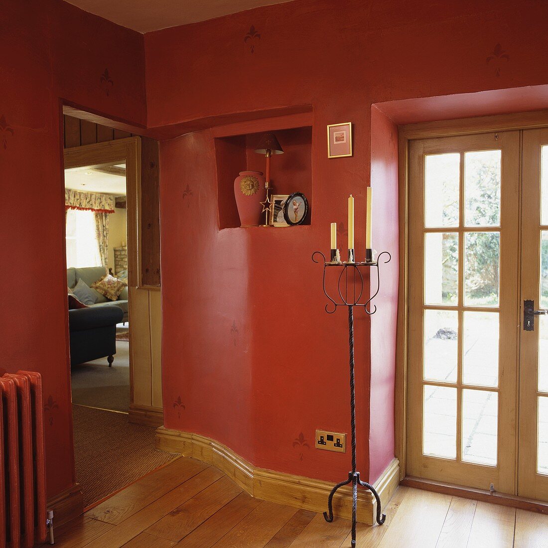 Diele mit roten Wänden, einer kleinen Mauernische und einem Holzfußboden