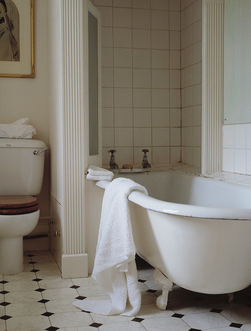 Traditionelles Badezimmer mit Keramikfliesen, Clawfoot- Badewanne und daran hängendem weissen Handtuch
