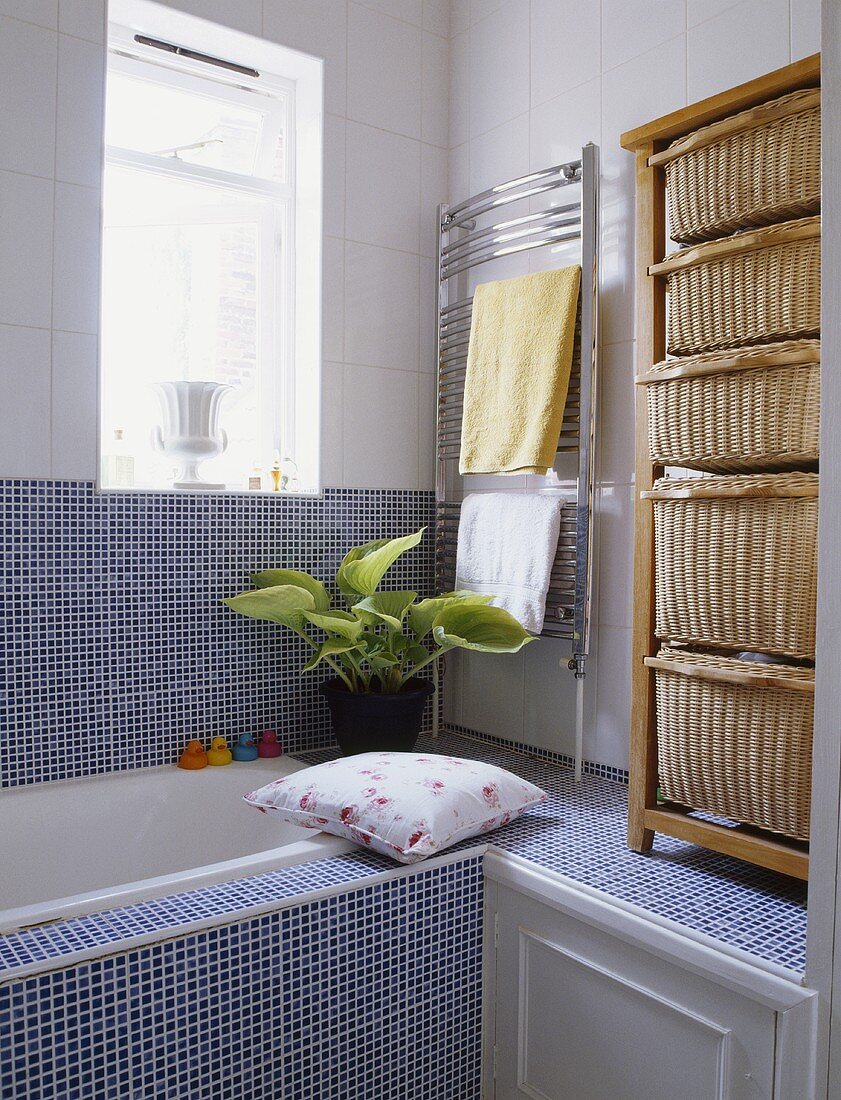 Badezimmer mit blauen Mosaikfliesen, einem vertikal stehenden Stahl-Heizkörper und mit einem hohen Regal mit Körben