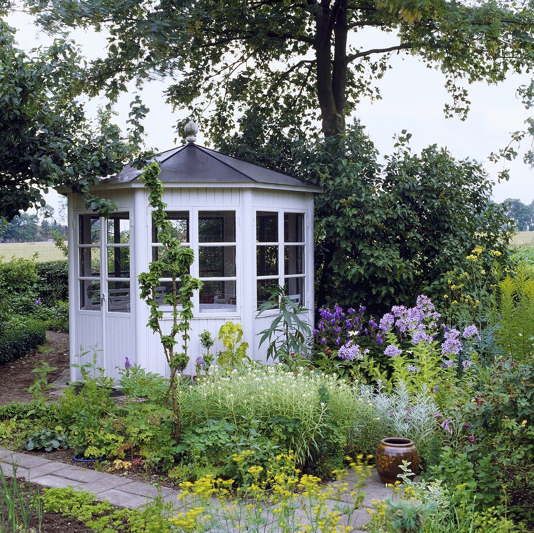 Gartenhaus aus weißem Holz unter Bäumen