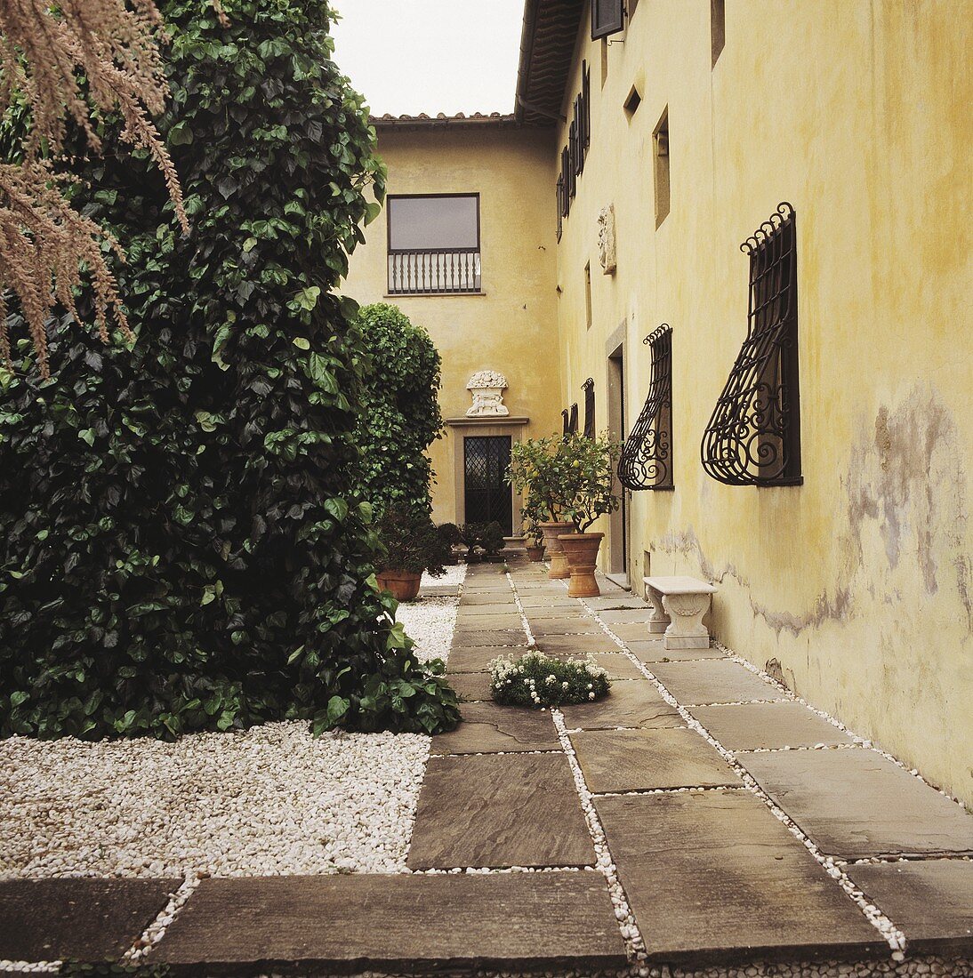 Gepflasterter Fussweg neben einem italienischen Landhaus