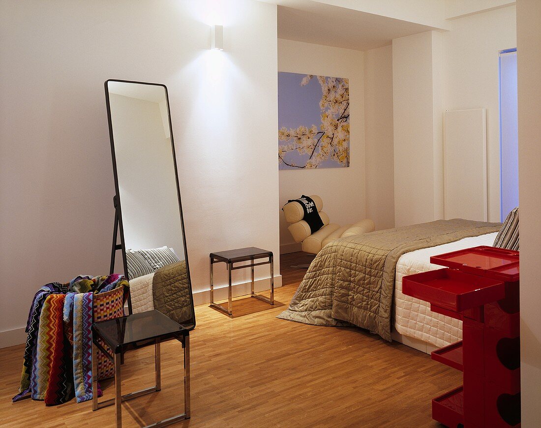A bedroom with a free-standing mirror and modern stools next to a bed