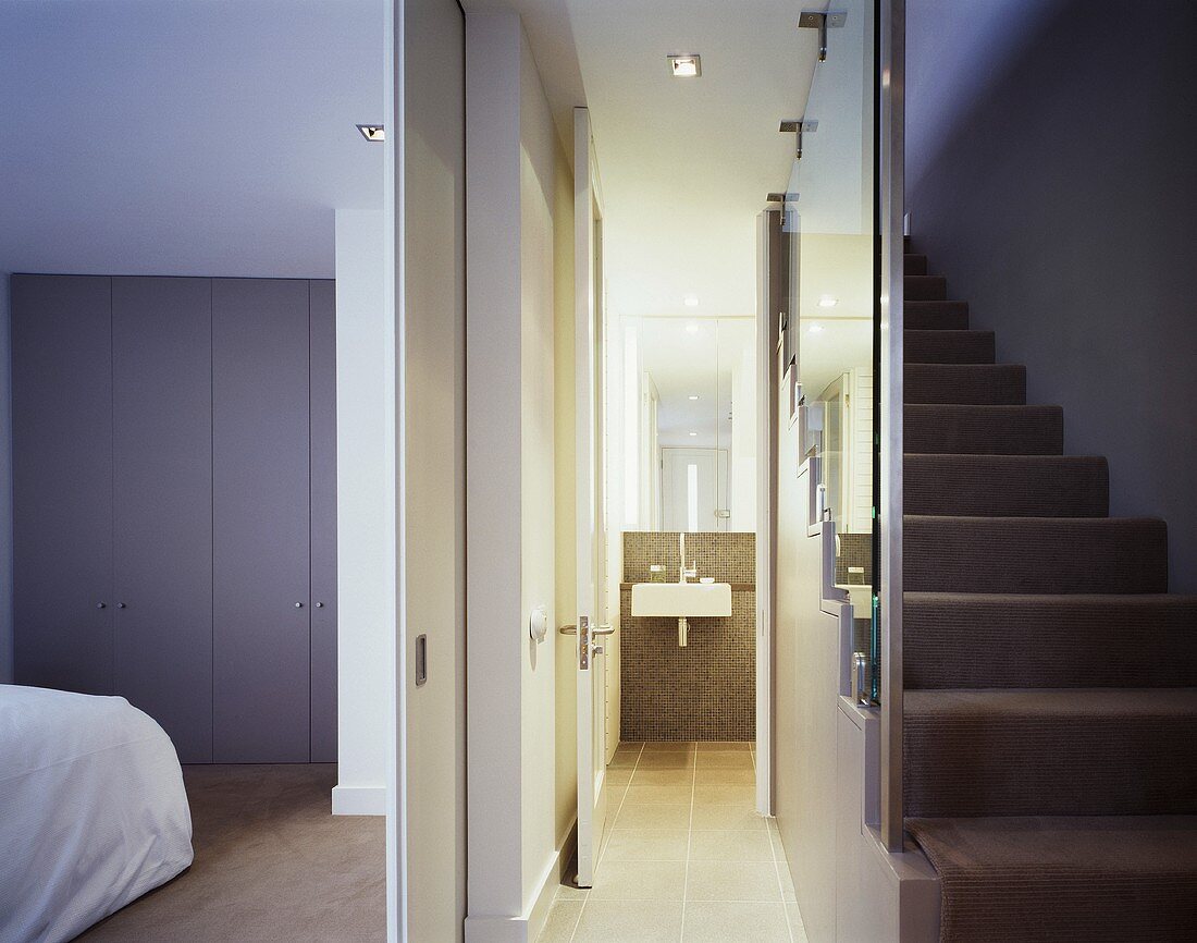 A view from a stairwell through an open door in to a bedroom and a bathroom