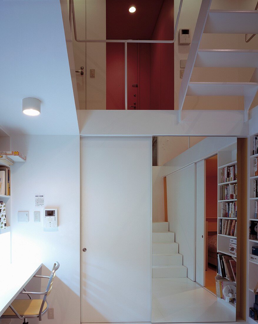 An open-plan study with an open sliding door integrated into the stairwell with a view of a gallery