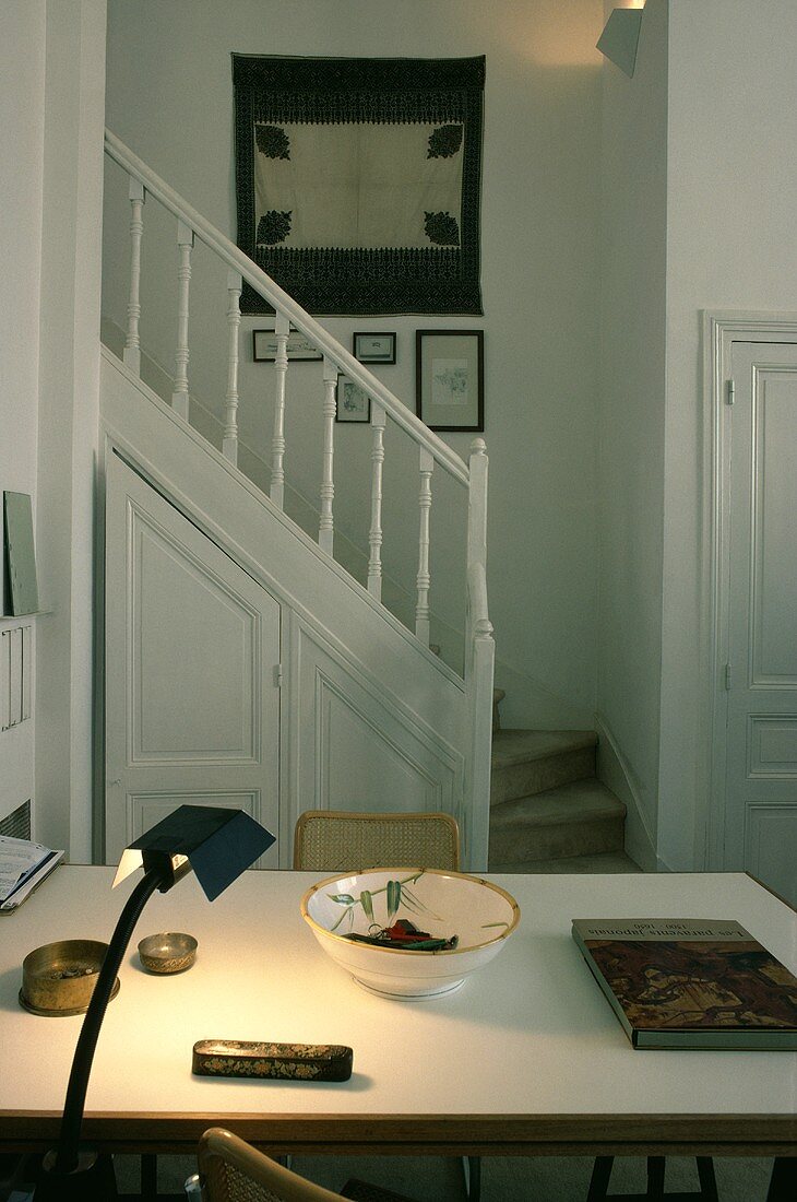 Kleiner Raum mit brennender Lampe am Tisch und Treppe im Hintergrund