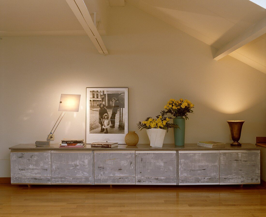 Metall Sideboard mit schwarz-weißem Foto, Büchern, Lampe und Blumenvasen in einem modernen Wohnzimmer