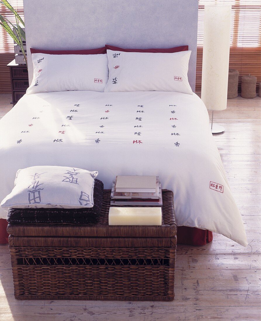 Truhe aus Korb vor Doppelbett mit asiatischen Schriftzeichen auf Bettwäsche