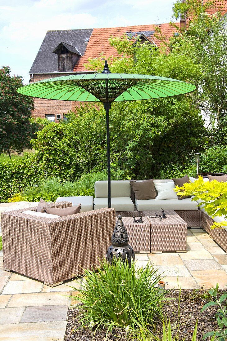 Wicker furniture on a terrace under a green sunshade