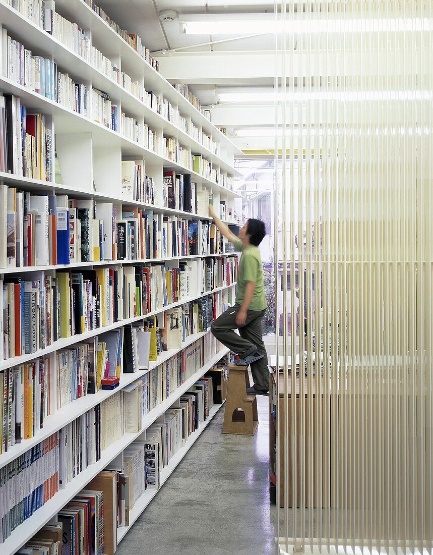 Mann steht auf Leiter vor Bücherregal