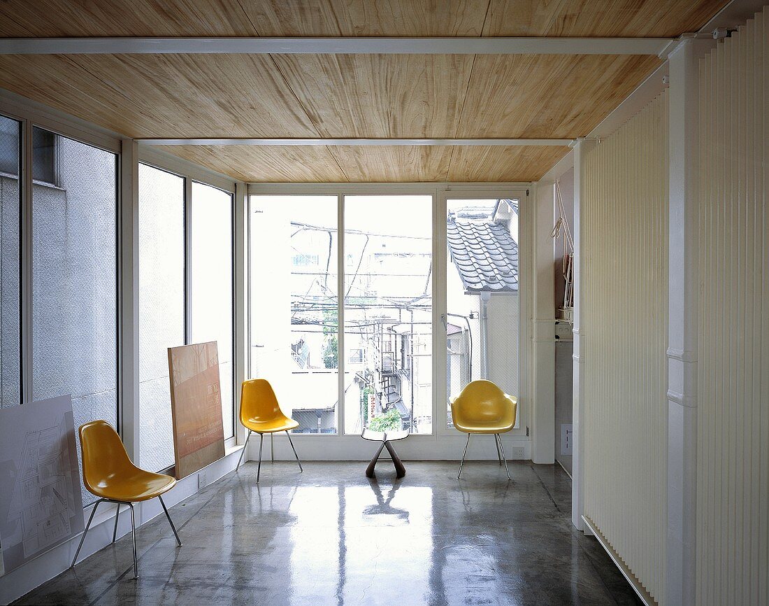 Gelbe Schalenstühle aus Kunststoff im Vorraum mit hochpoliertem Betonboden