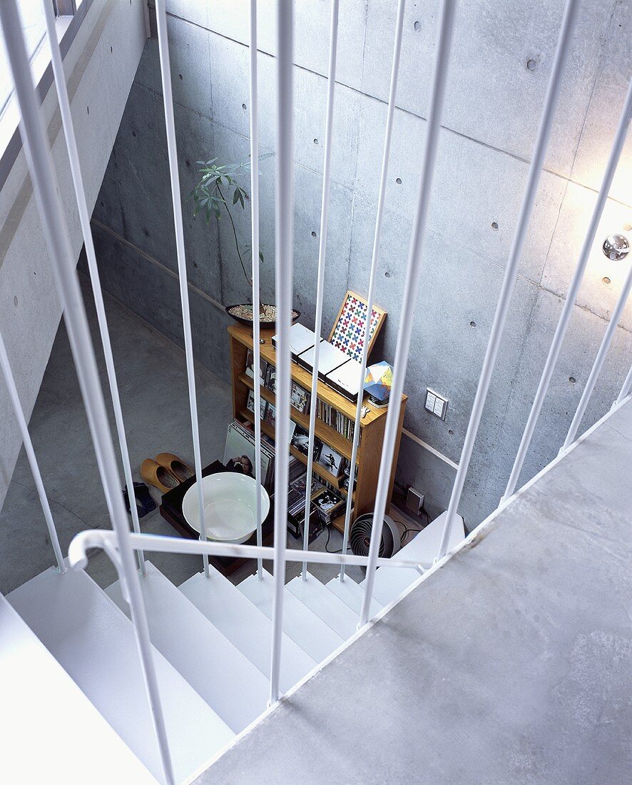 An open stairway with a view of a shelf in front of a concrete wall