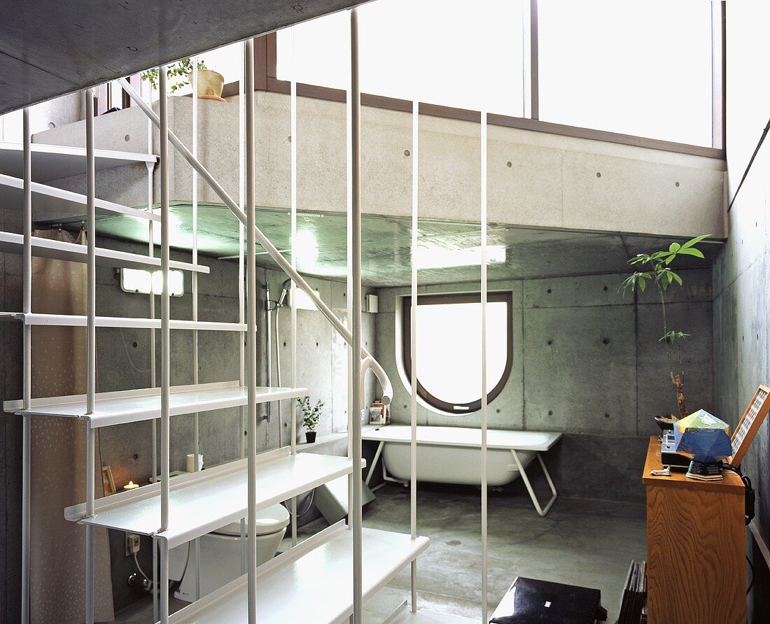 An open stairway with a view into a concrete bathroom