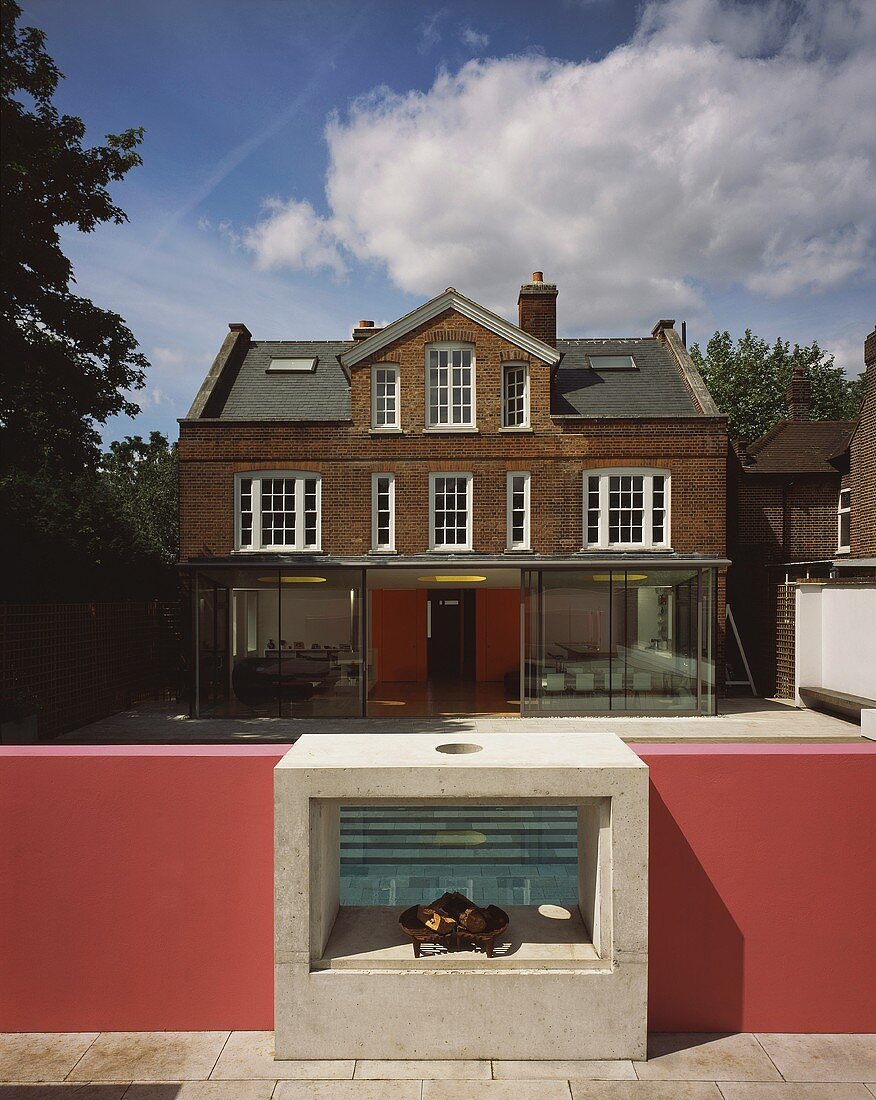 Gartenansicht eines englischen Hauses mit Ziegelfassade und modernem Wintergarten