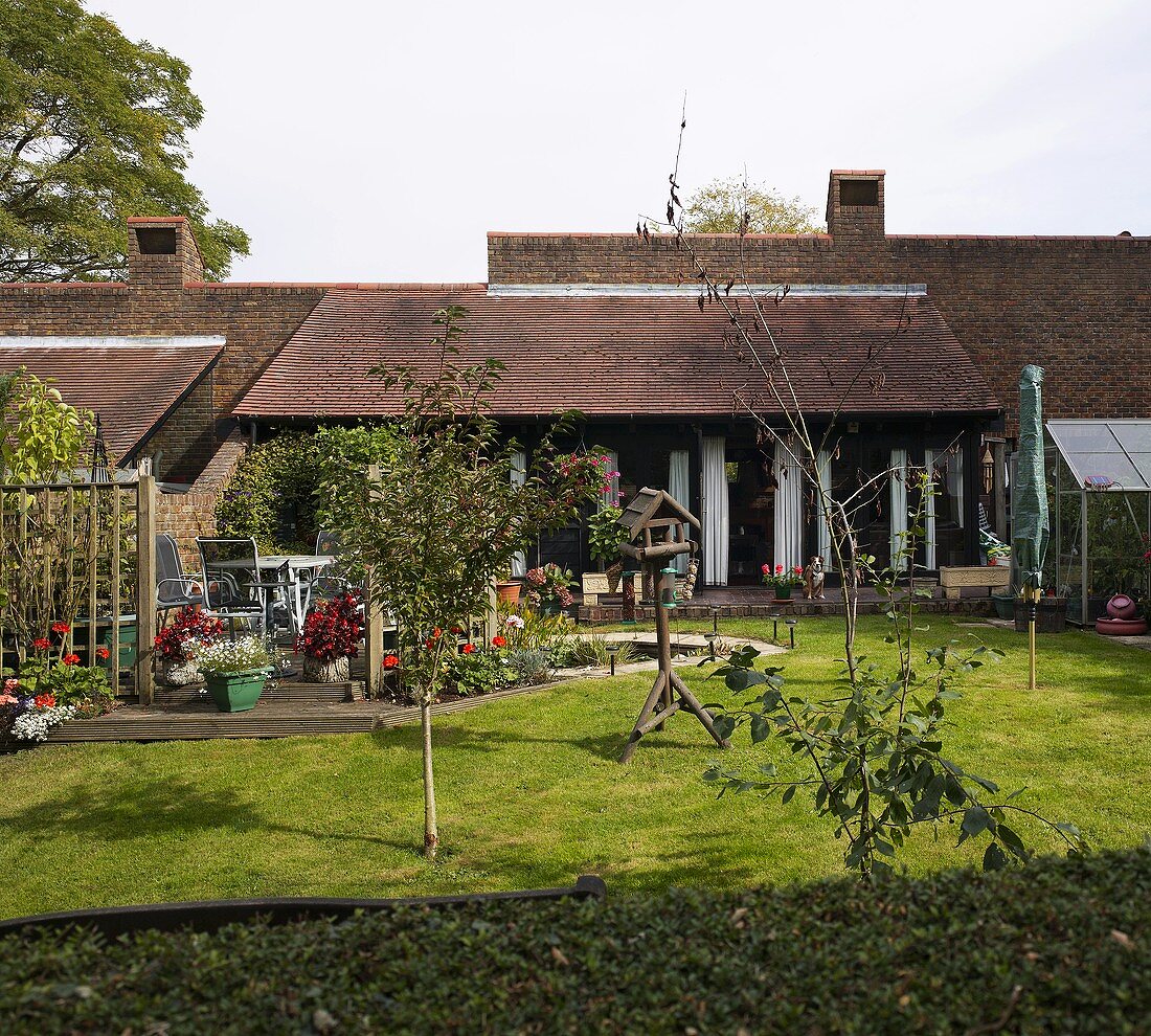 A garden with a terrace in front of an English-style house