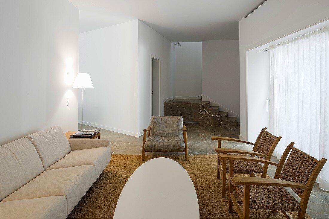Offener weisser Wohnraum mit hellem Sofa und rustikalen Sesseln