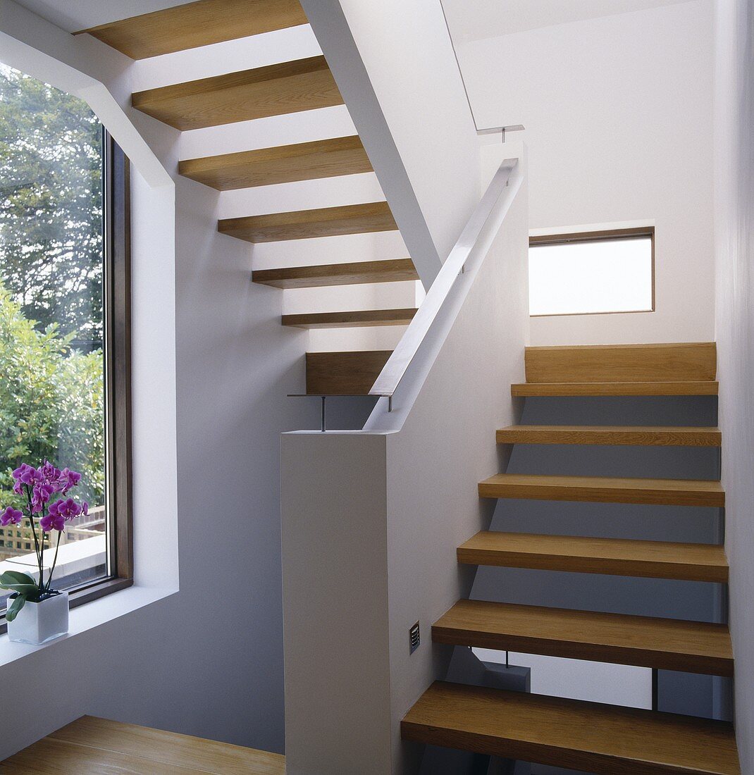 A modern white staircase with wooden stairs