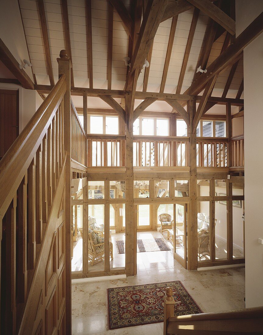 A renovated country house with an open hallway built of wood and glass and a gallery under the roof