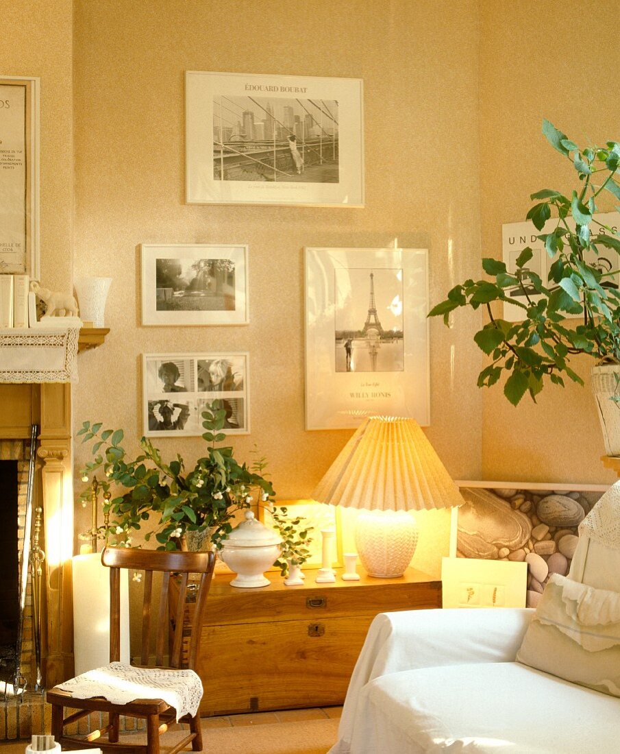 Schwarzweiss-Fotografien über Holztruhe mit brennender Lampe in modernem Wohnzimmer in Naturfarben
