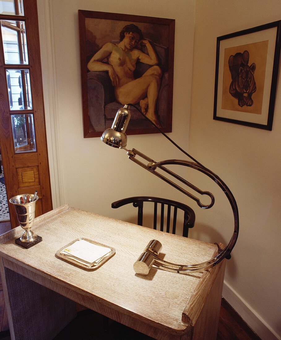 30er-Jahre Stahl-Schreibtischlampe und antiker Holzstuhl vor modernen Gemälden in kleiner Schreibecke