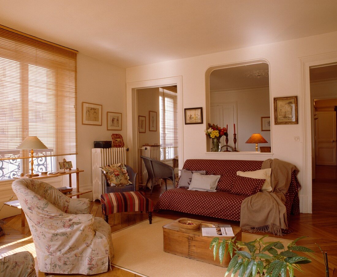 Holzkiste als Couchtisch in lässigem Wohnzimmer mit Spiegel in Türrahmen und Maueröffnung zu Nebenzimmer