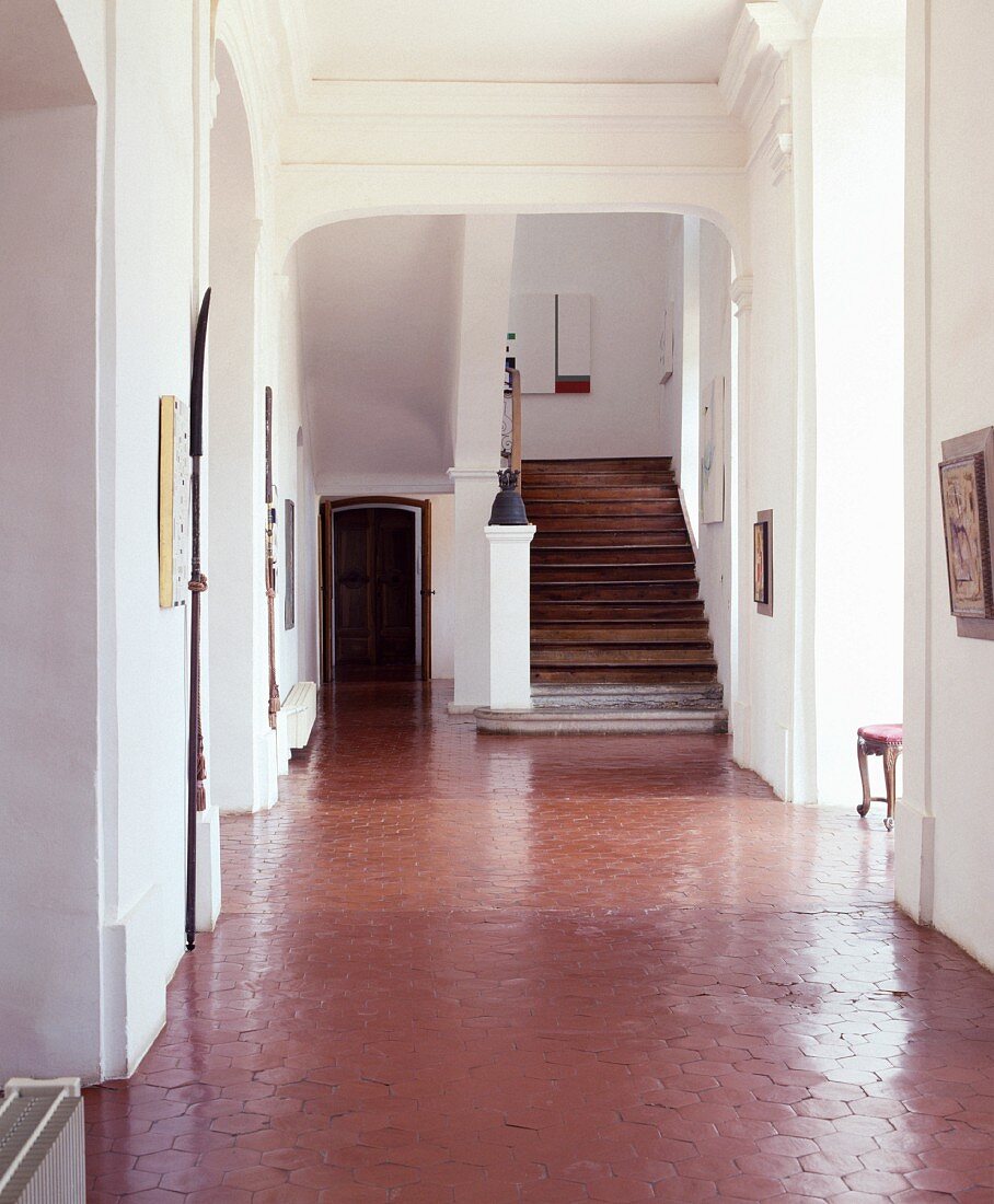 Blick auf Treppe in grosszügigem französischem Landhaus mit sechseckigen, polierten Terracotta-Fliesen in Eingangshalle