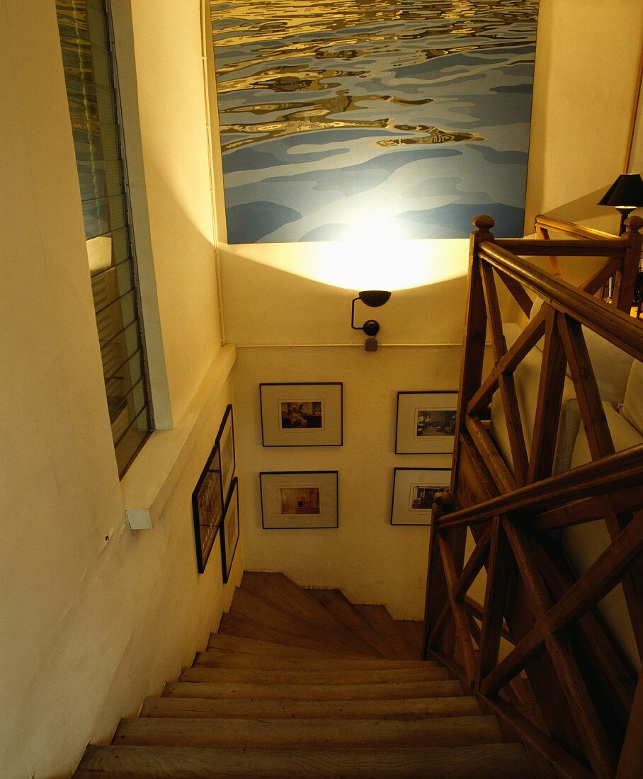 Angestrahltes, blaues Wasserbild über Treppenabgang mit auffälligem Holzgeländer