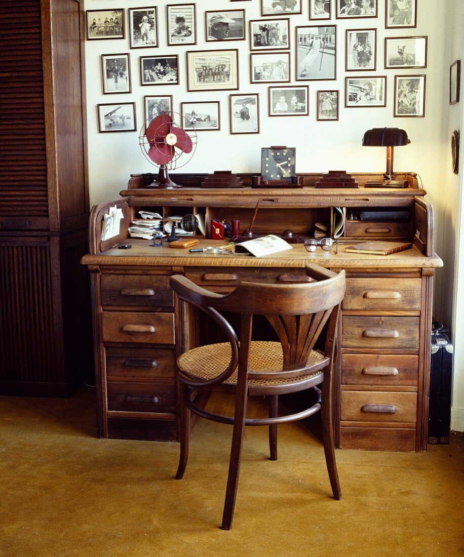 Schwarzweiss-Fotografien an der Wand über altem Sekretär und Bugholzstuhl mit Sitzgeflecht