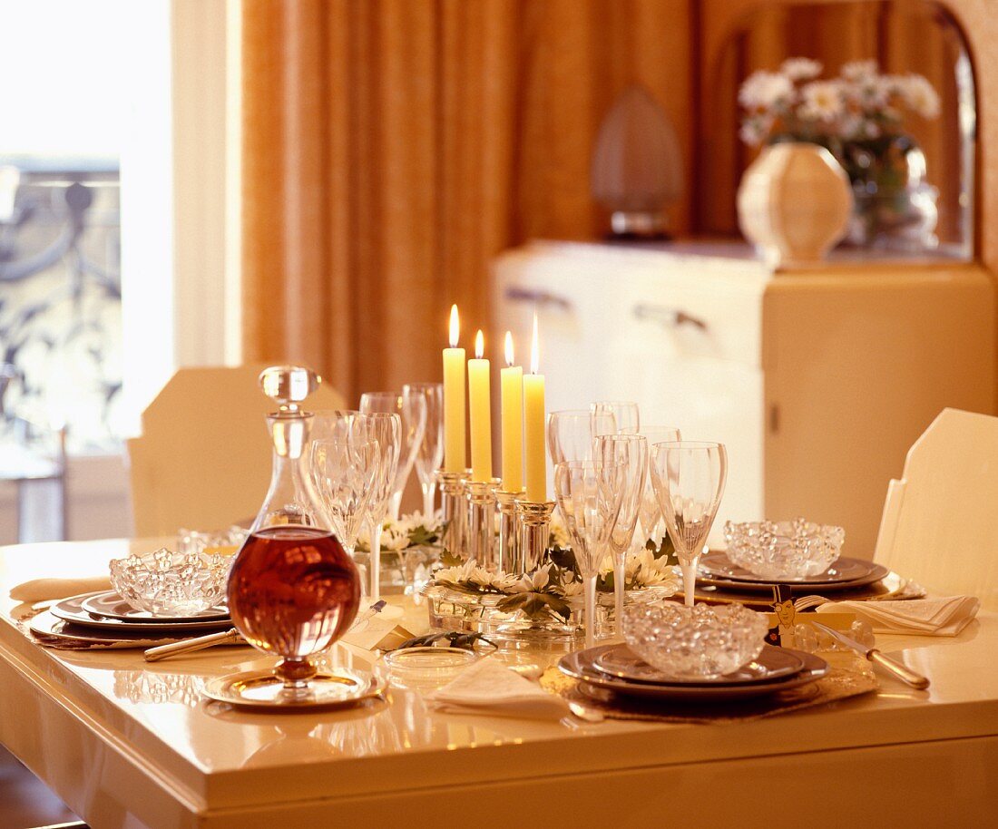 Dekanter und Weingläser auf festlich gedecktem Tisch mit brennenden Kerzen