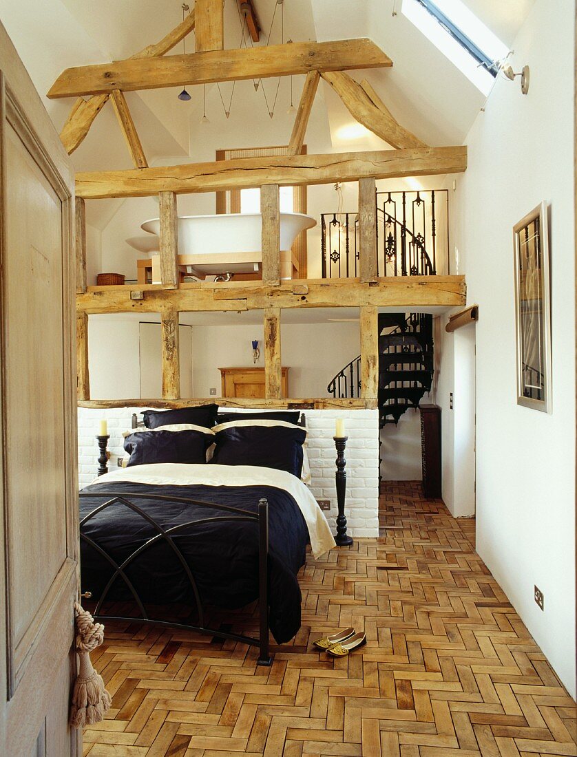 Offenes Schlafzimmer in ausgebautem Scheunendachstuhl mit Wendeltreppe auf Galeriebad