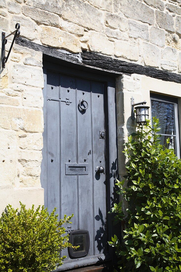 Antike, blaue Holztür in Natursteinfassade eines alten Landhauses