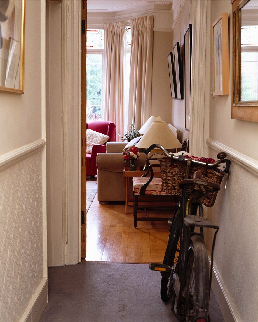 Altmodisches Fahrrad in kleinem Gang mit offener Tür zum traditionellen Wohnzimmer