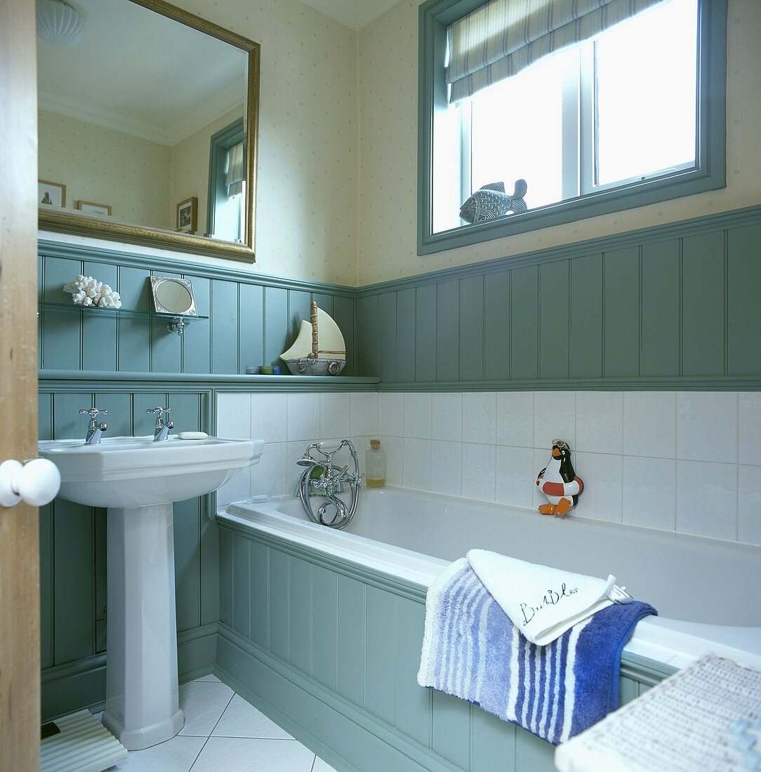 Türkis getäfeltes Badezimmer mit Badewanne und grossem Spiegel über dem Waschbecken