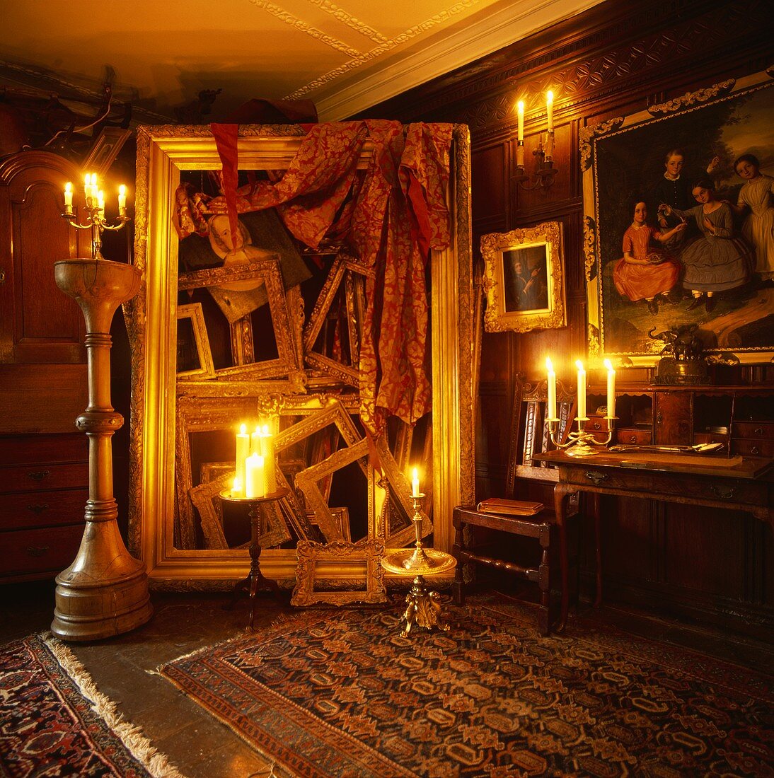 Raumhohe Skulptur aus leeren, vergoldeten Bilderrahmen stimmungsvoll mit Kerzenlicht beleuchtet in Wohnraum mit Holzvertäfelung