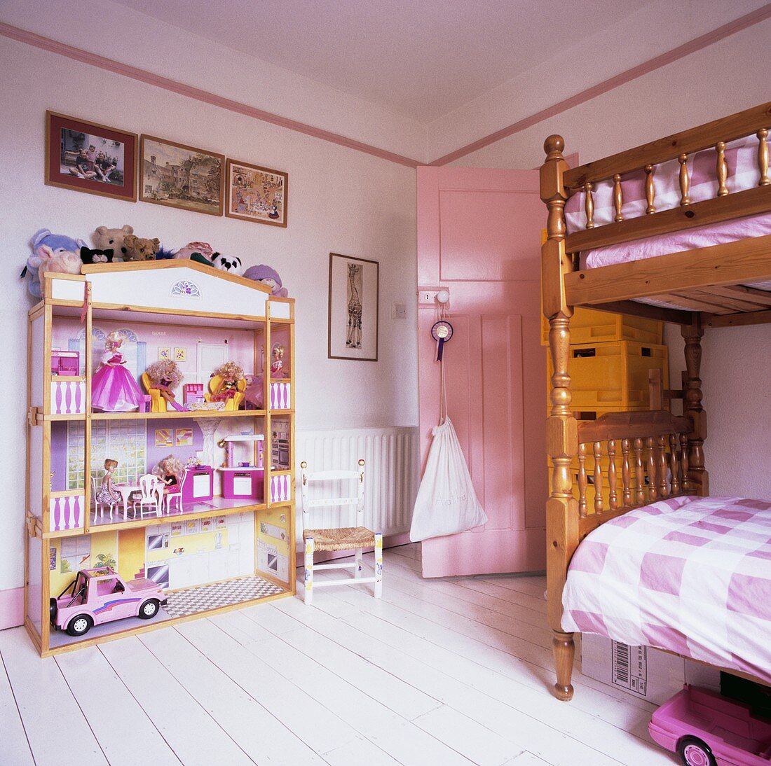 Grosses Barbie-Puppenhaus und rustikales Hochbett in Kinderzimmer mit weissen Dielen und rosafarbener Tür