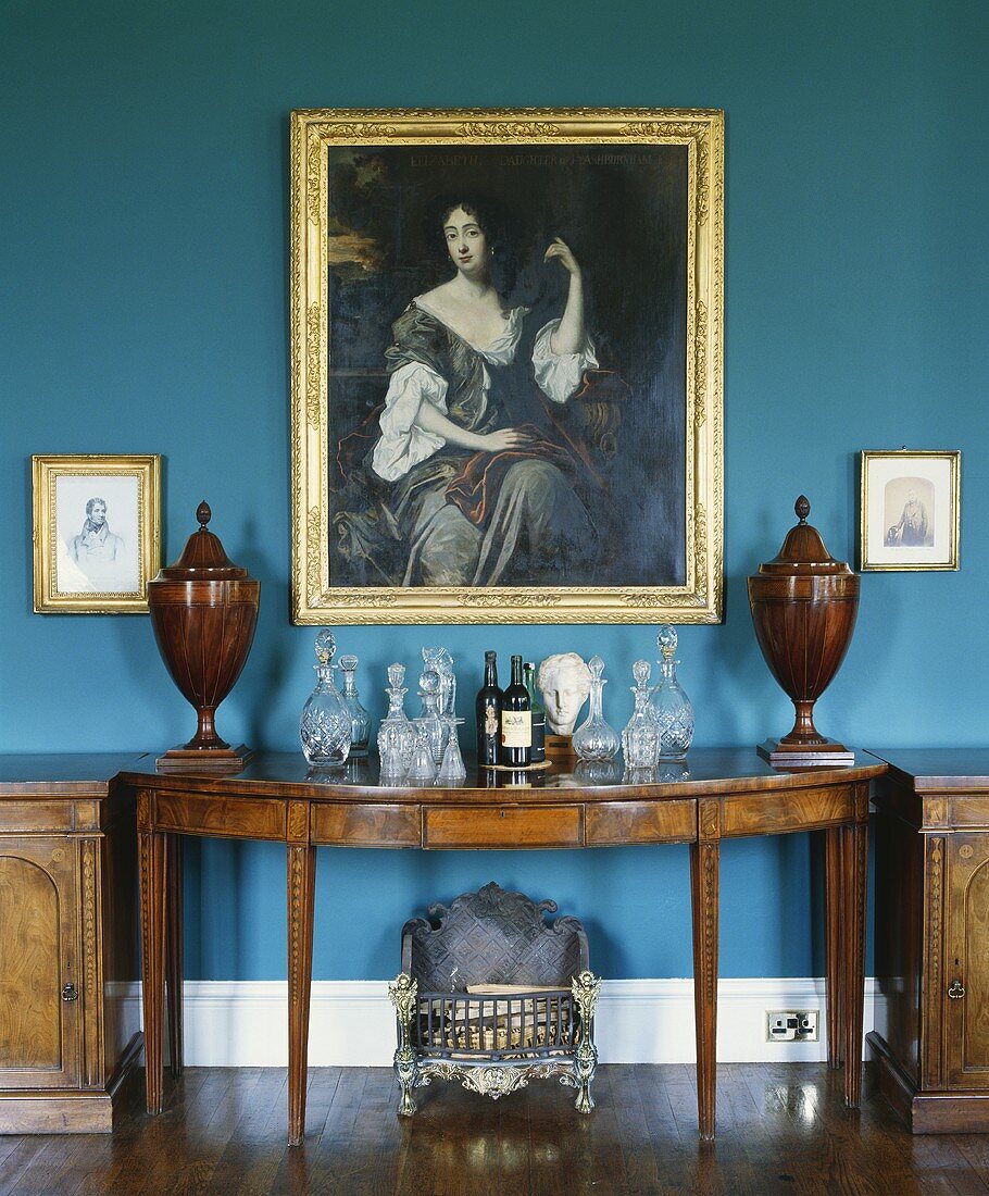 Grosses Ölgemälde über einer antiken Konsole in einem Wohnzimmer mit blauer Wand