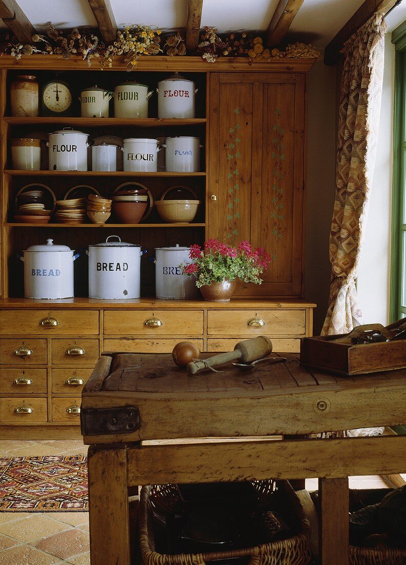 Eine Anrichte aus Kiefer mit weissen Emaille-Vorratsdosen und ein alter Metzgerblock in einer Landhausküche