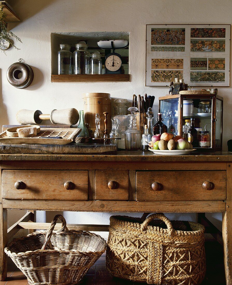 Verschiedene Küchenutensilien auf einem antiken Holztisch mit Schublade