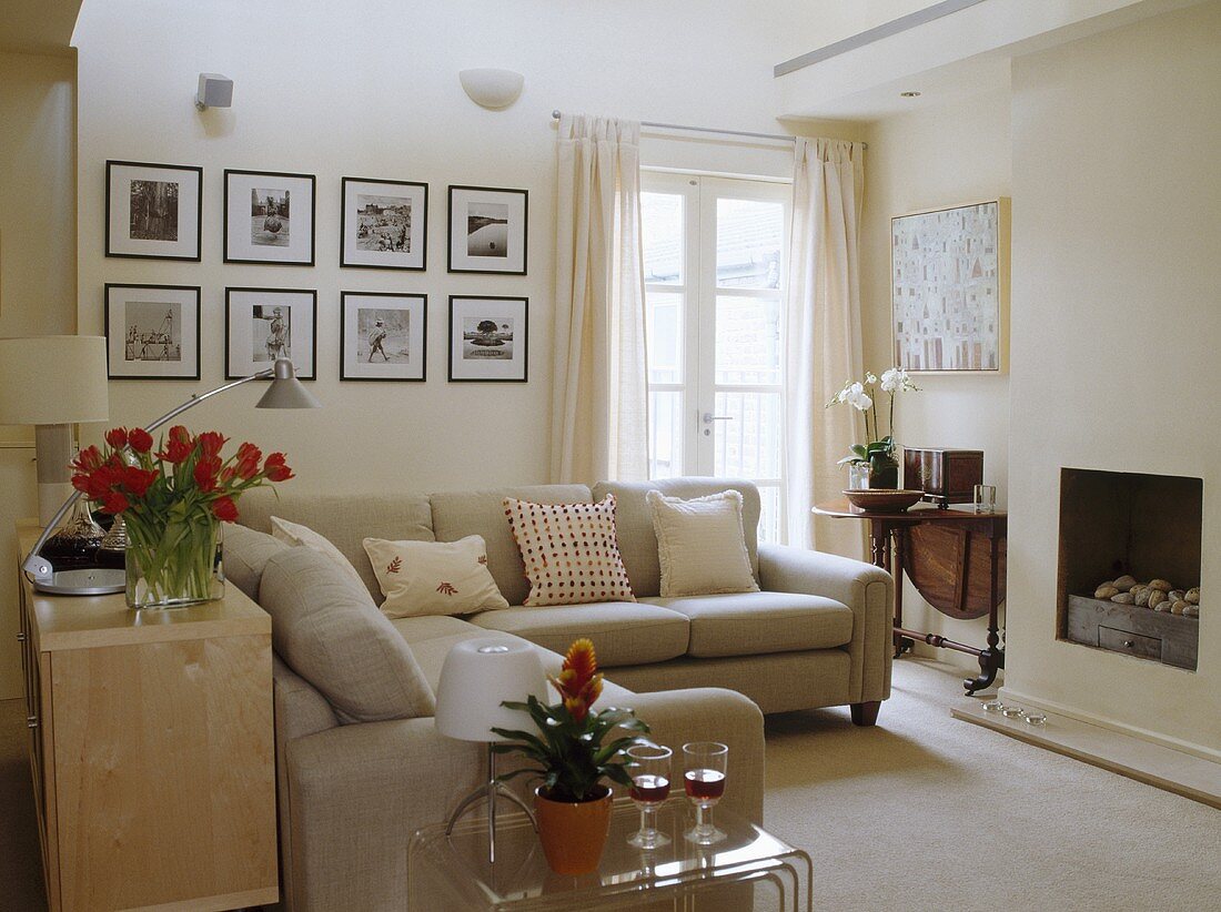 Beige Sofas und gerahmte Schwarzweiß-Fotografien im cremefarbenen, zeitgenössischen Wohnzimmer
