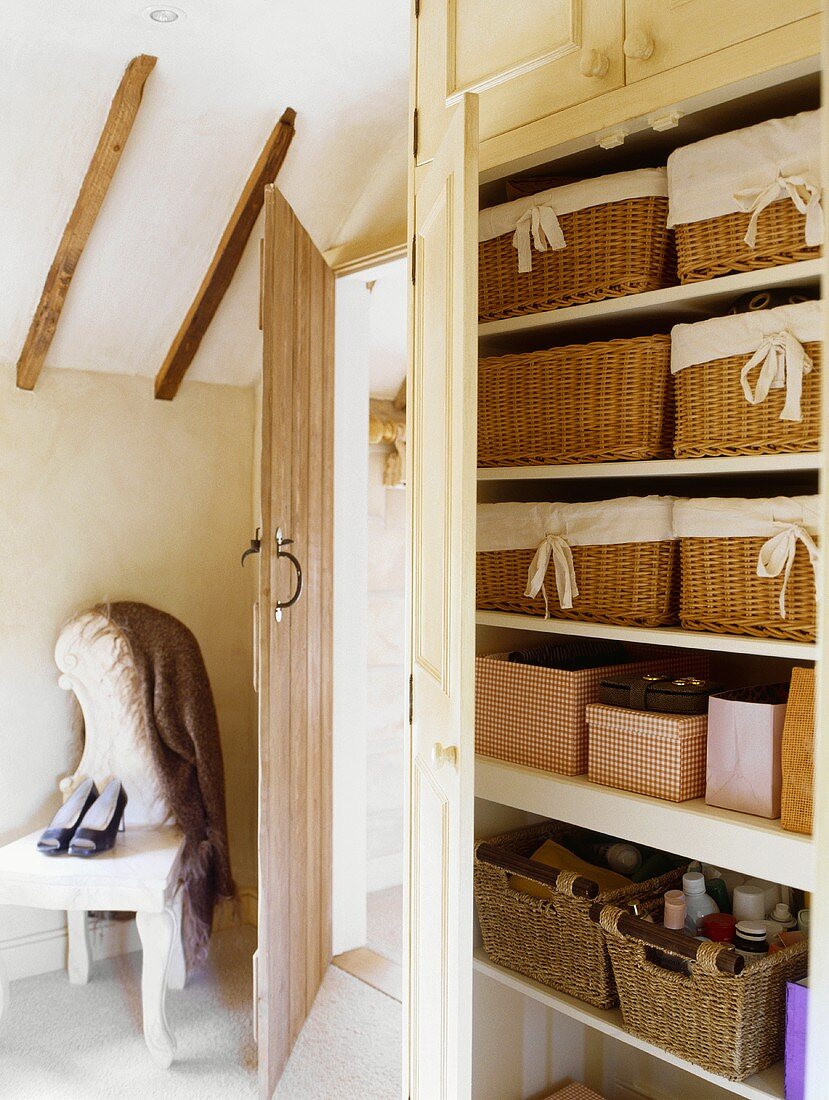 Blick in einen grossen Schrank mit Ordnungskörben in einem ländlichen Schlafzimmer