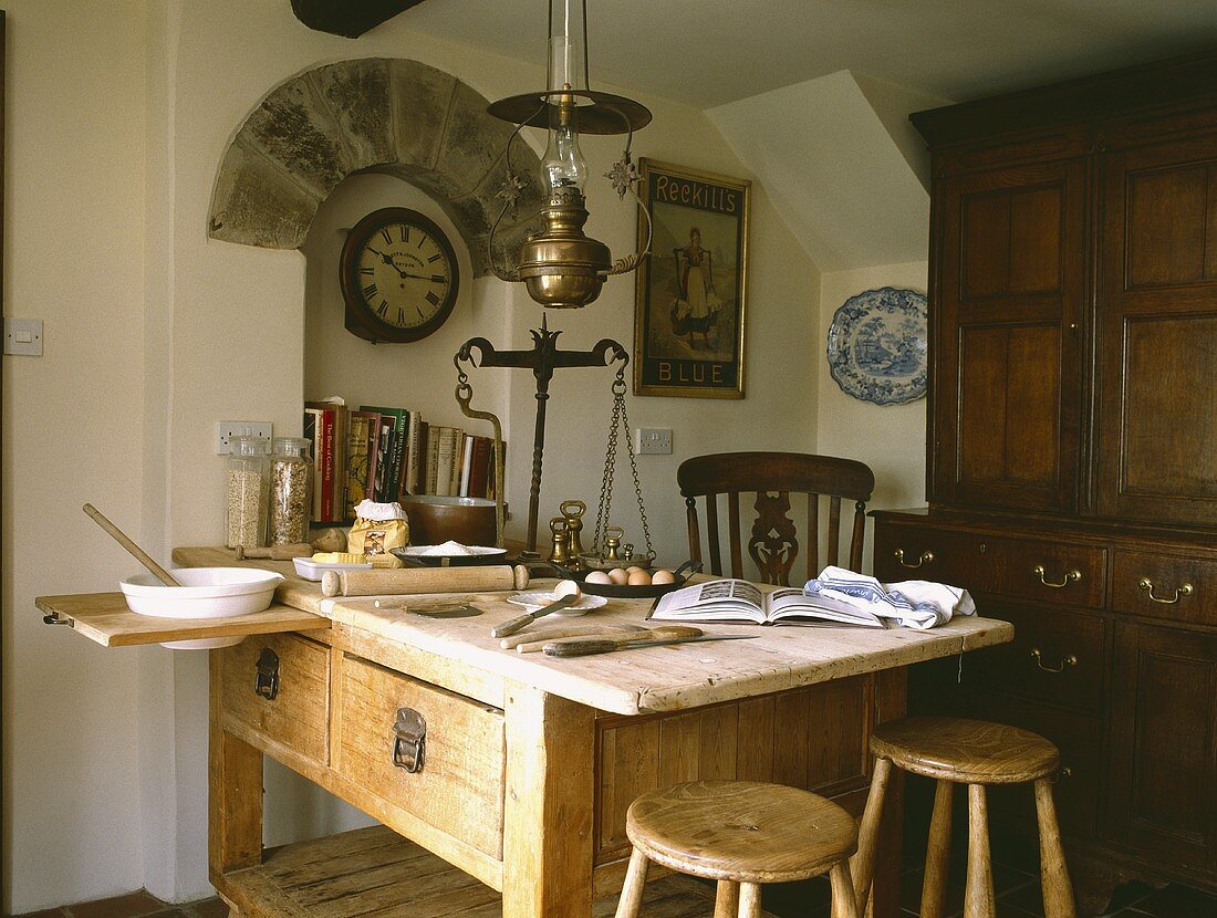 Altmessing Waage auf viktorianischem Bäckertisch in Landhausküche mit Uhr unter Steinbogen