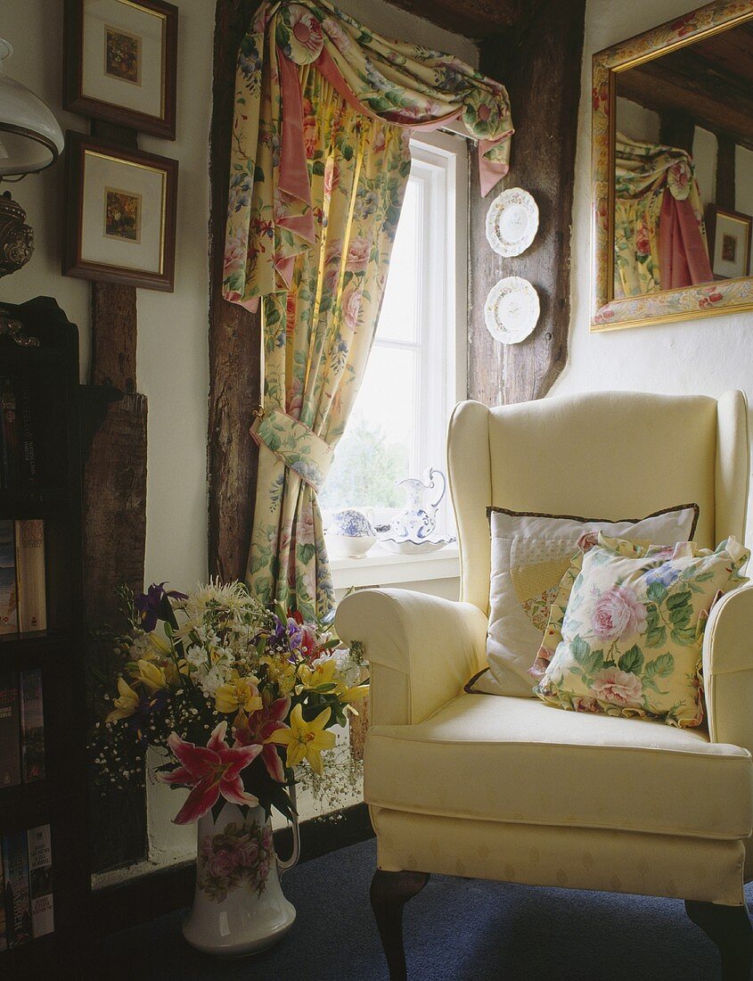 Cremefarbener Sessel und Vorhänge mit floralen Mustern im Landhaus-Wohnzimmer
