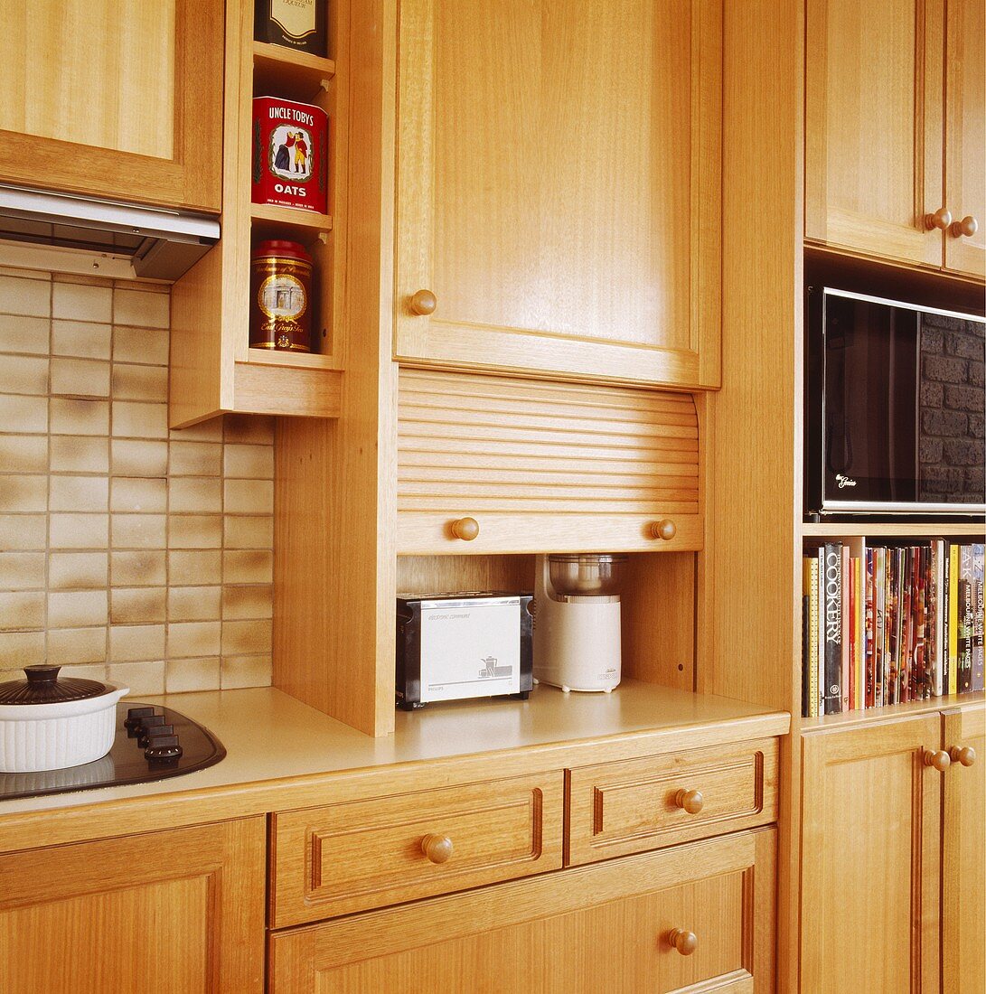 Ein Toaster und ein Mixer stehen in einem Küchenschrank mit einer Tür, die man hochklappen kann