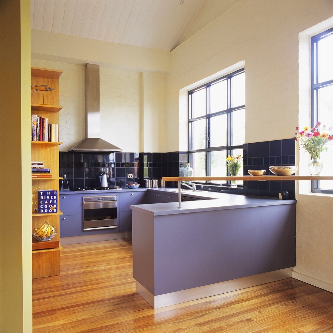 Violette Einbauschränke und Arbeitsflächen in einer modernen weißen Küche mit einen hellen Parkettboden