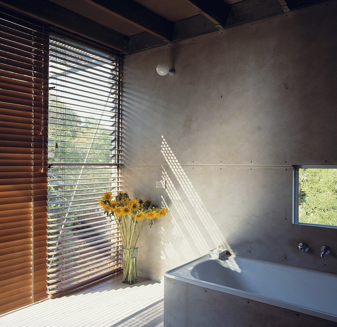 Ein modernes Badezimmer mit Steinmauer-Wänden und Holz-Jalousien, die für Sichtschutz sorgen, ausgestattet