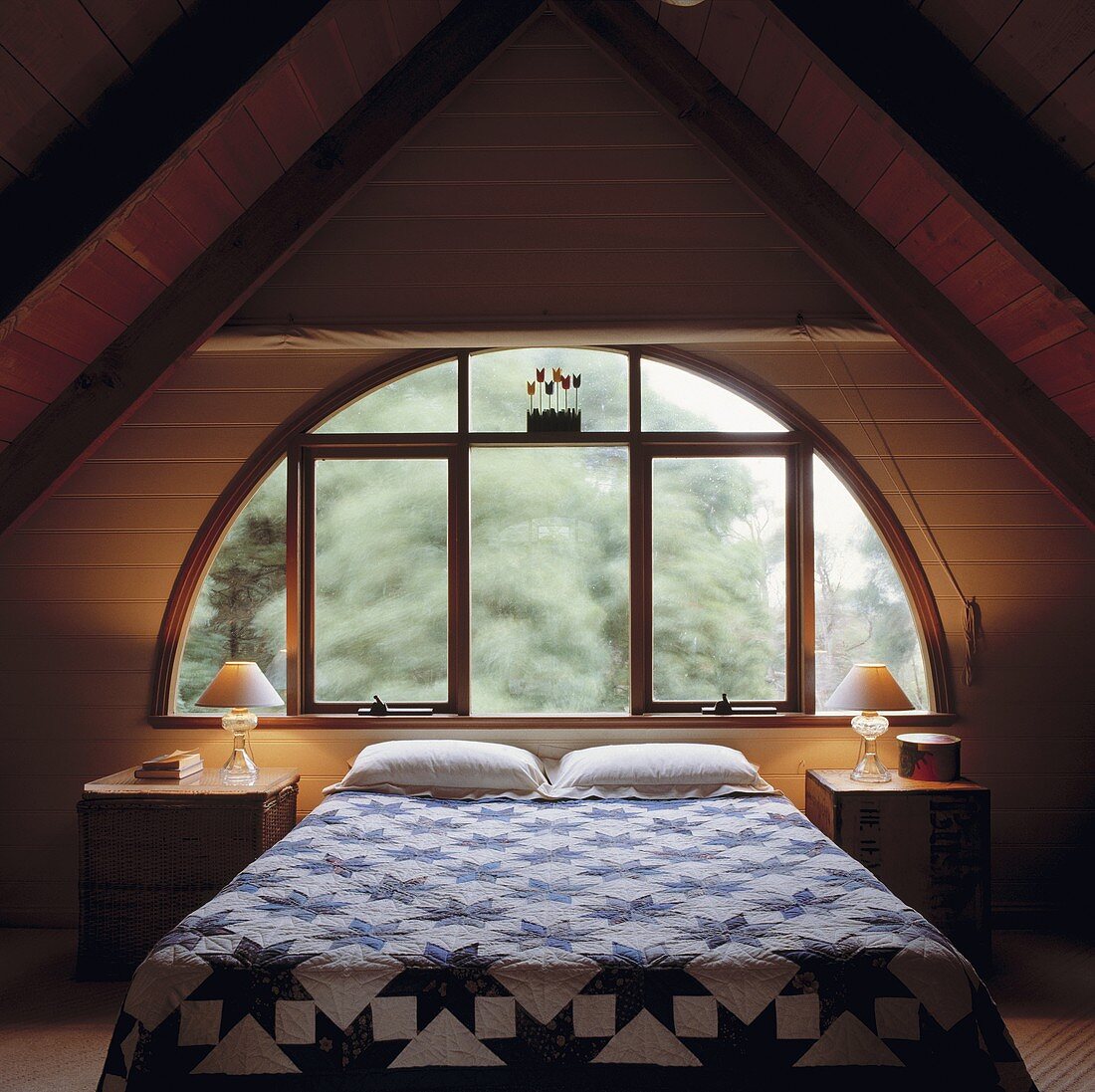 Ein Loft Schlafzimmer mit einem halbkreisförmigen Fenster und beidseitigen Dachschrägen