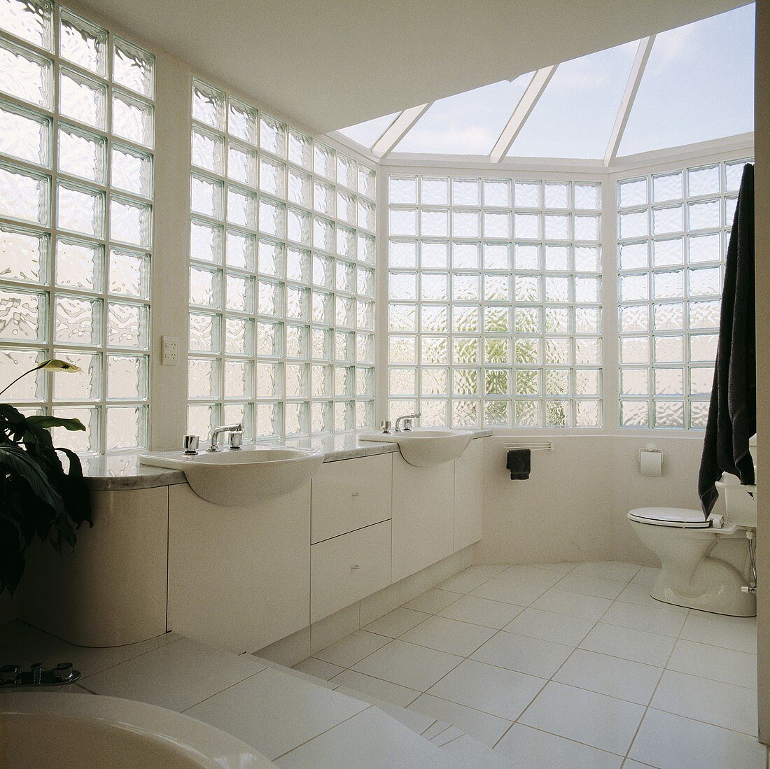 Modernes weisses Bad mit Wänden aus Glasbausteinen und Glasdach