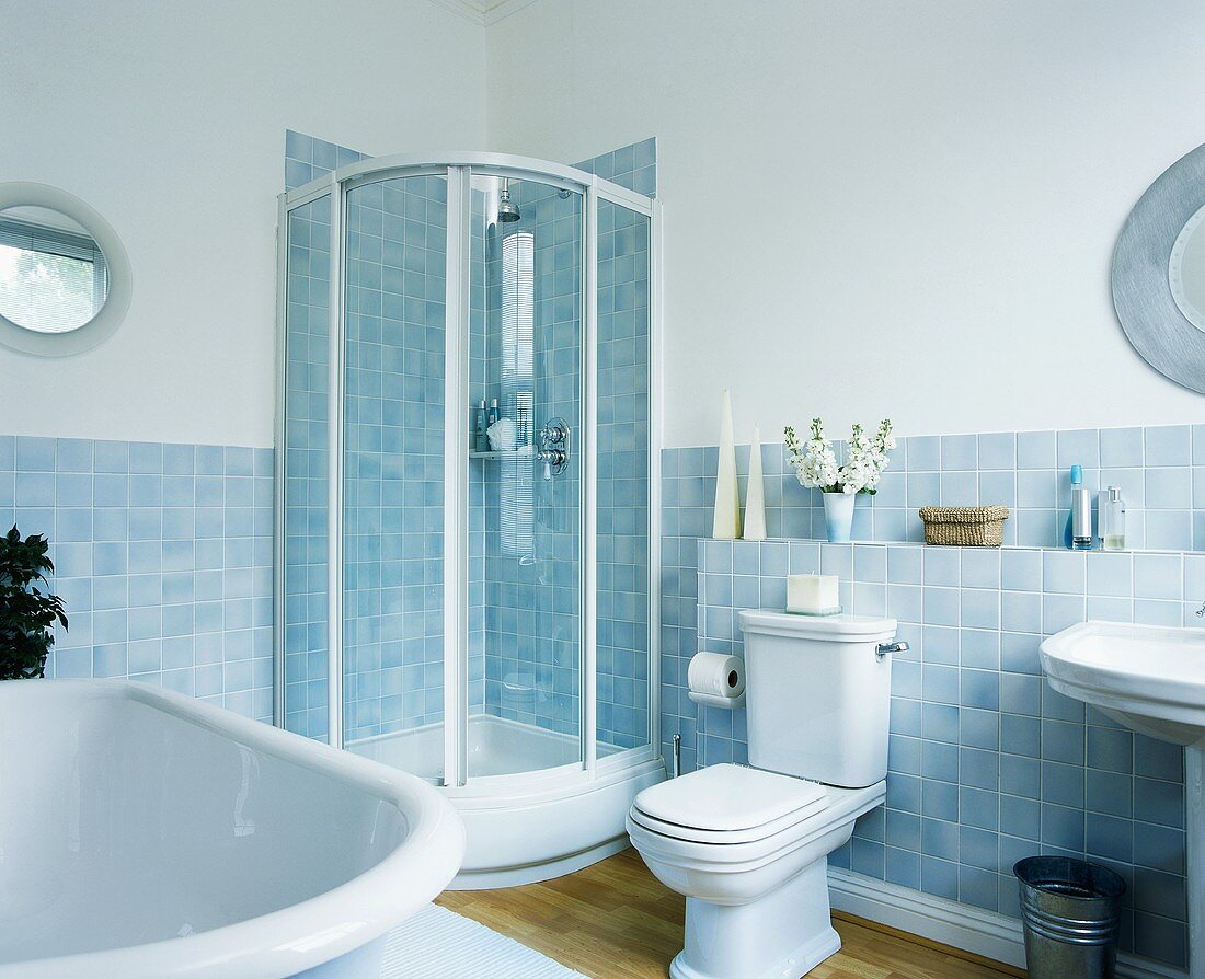 Weisses, traditionelles Bad mit Übereck-Duschkabine, pastellblau changierenden Wandfliesen und Parkettboden